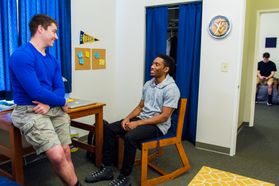 Two male students hang out in University Hall room